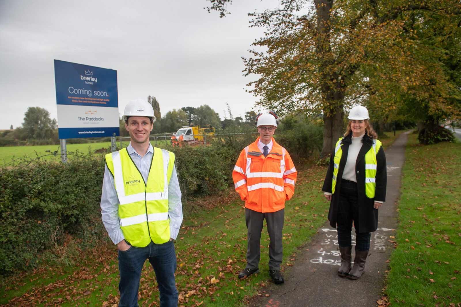 Three people in hard hats in front of the paddocks development