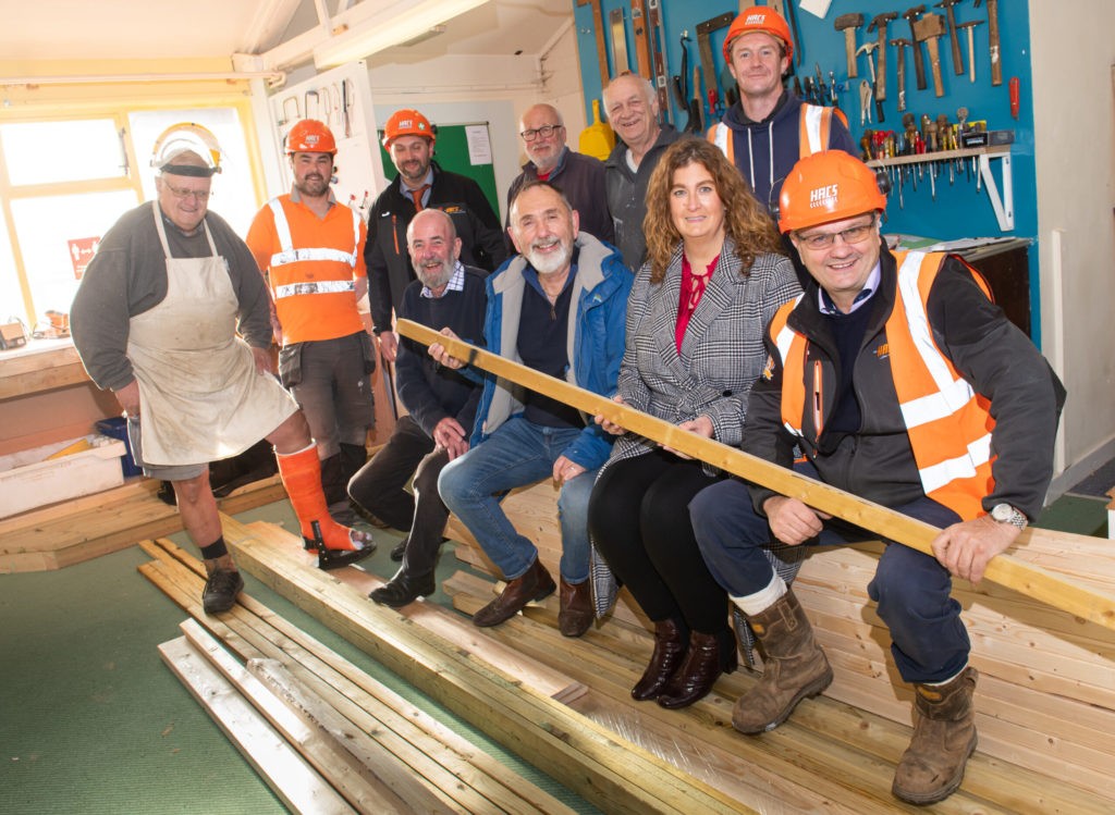 Several people in hard hats sat on some timber
