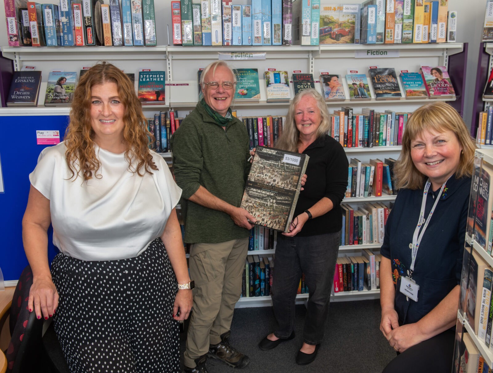 Four people in a library, one being presented with an item