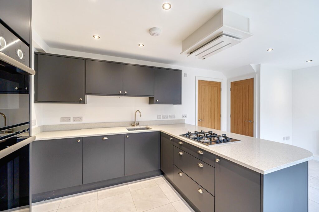kitchen with black cabinets and white tops with integrated oven and hob